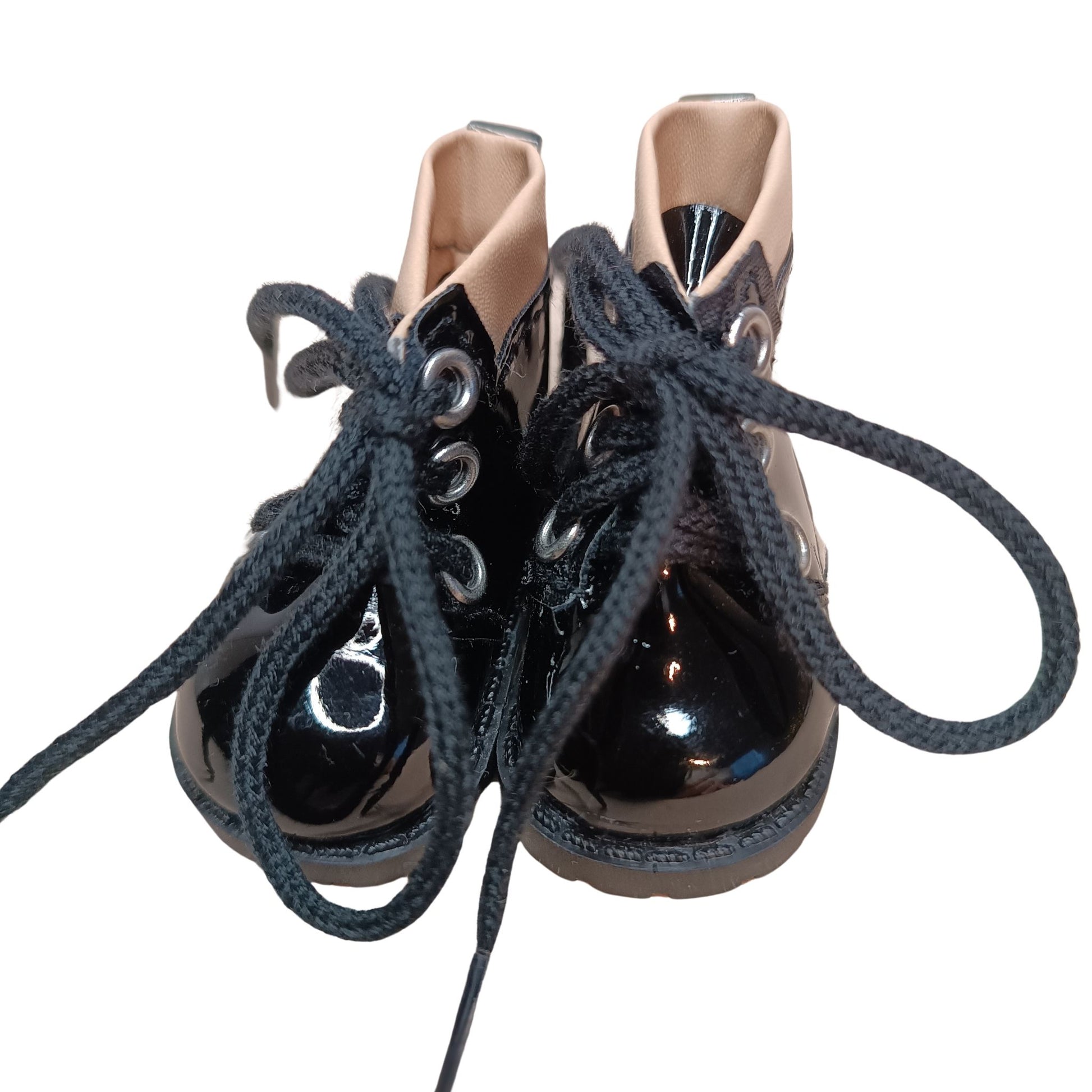 Glossy black lace-up boots with beige cuffs, designed for 32 cm Paola Reina dolls. Featuring black laces, metal eyelets, and a chunky sole for a bold fashion statement.