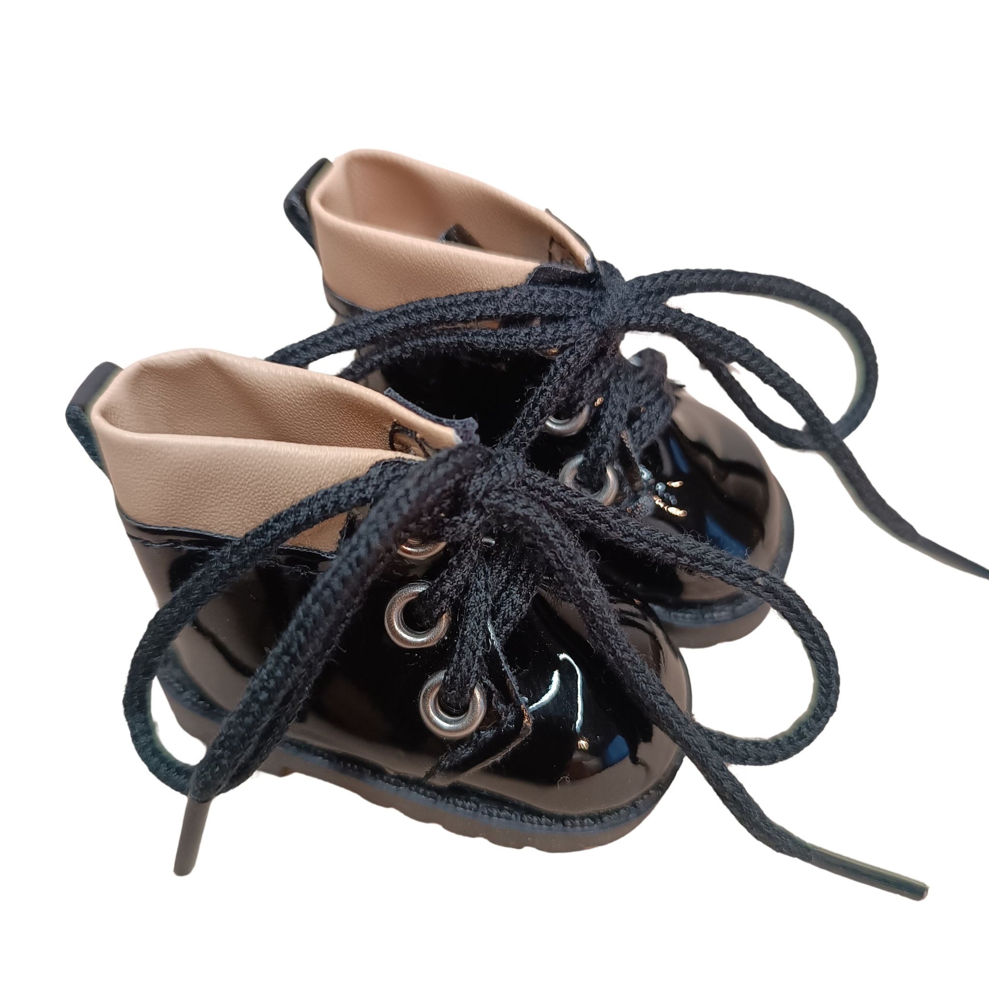 Glossy black lace-up boots with beige cuffs, designed for 32 cm Paola Reina dolls. Featuring black laces, metal eyelets, and a chunky sole for a bold fashion statement