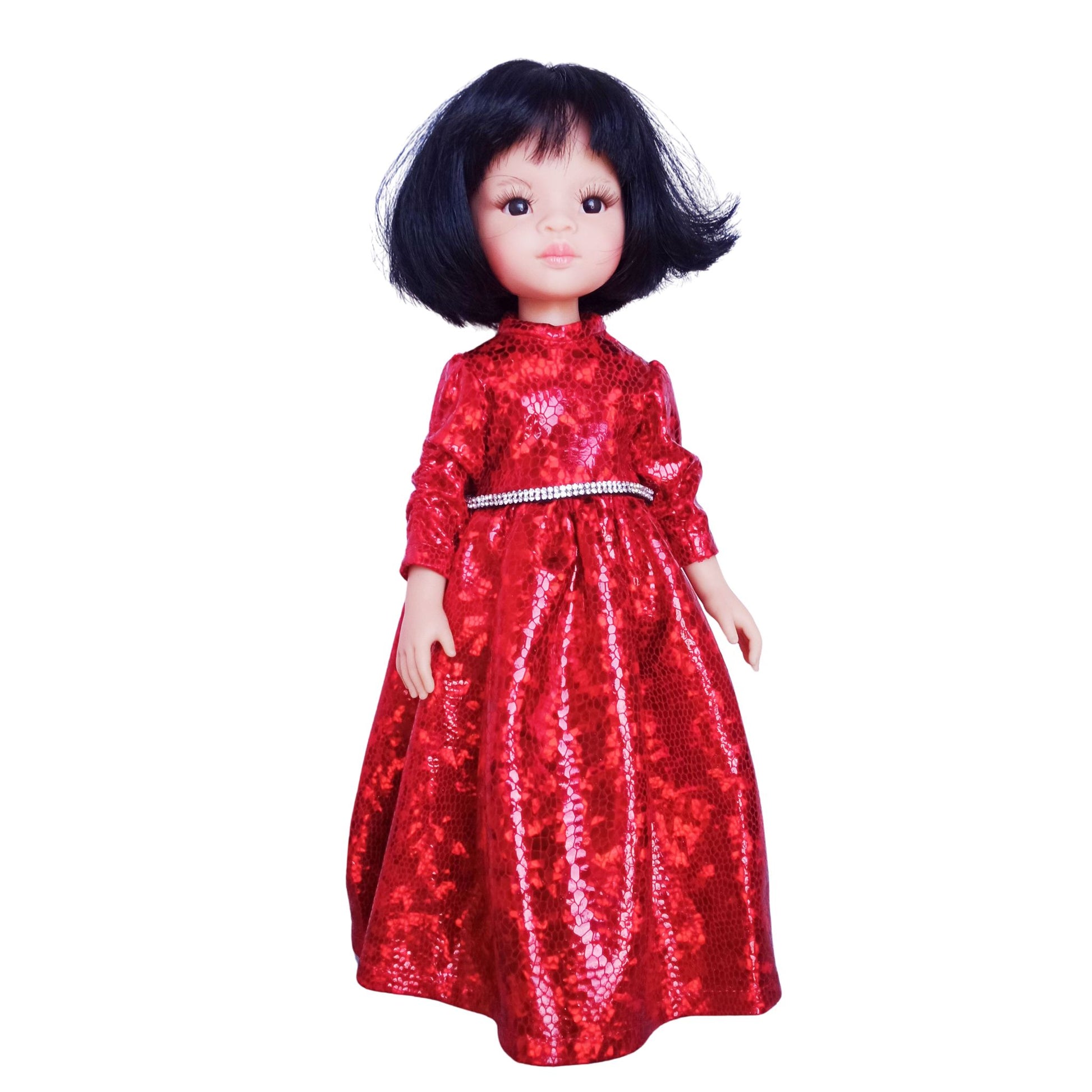 Paola Reina 32 cm doll wearing a red sparkling dress with a rhinestone belt and black patent leather shoes, standing against a white background.